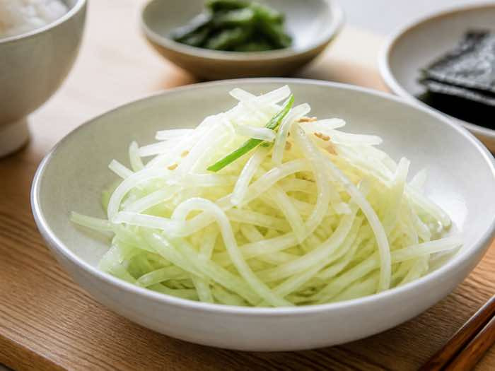 Korean julienned radish salad with a light wasabi vinegar dressing in a small ceramic bowl